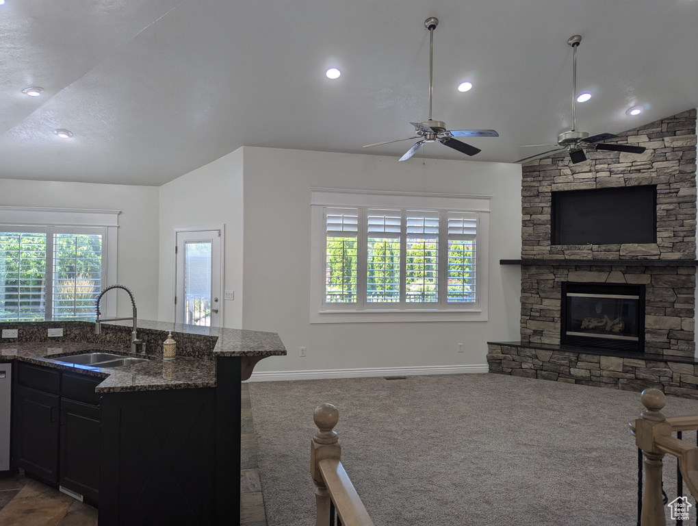 Kitchen featuring open floor plan, carpet, plenty of natural light, dark stone counters, and lofted ceiling