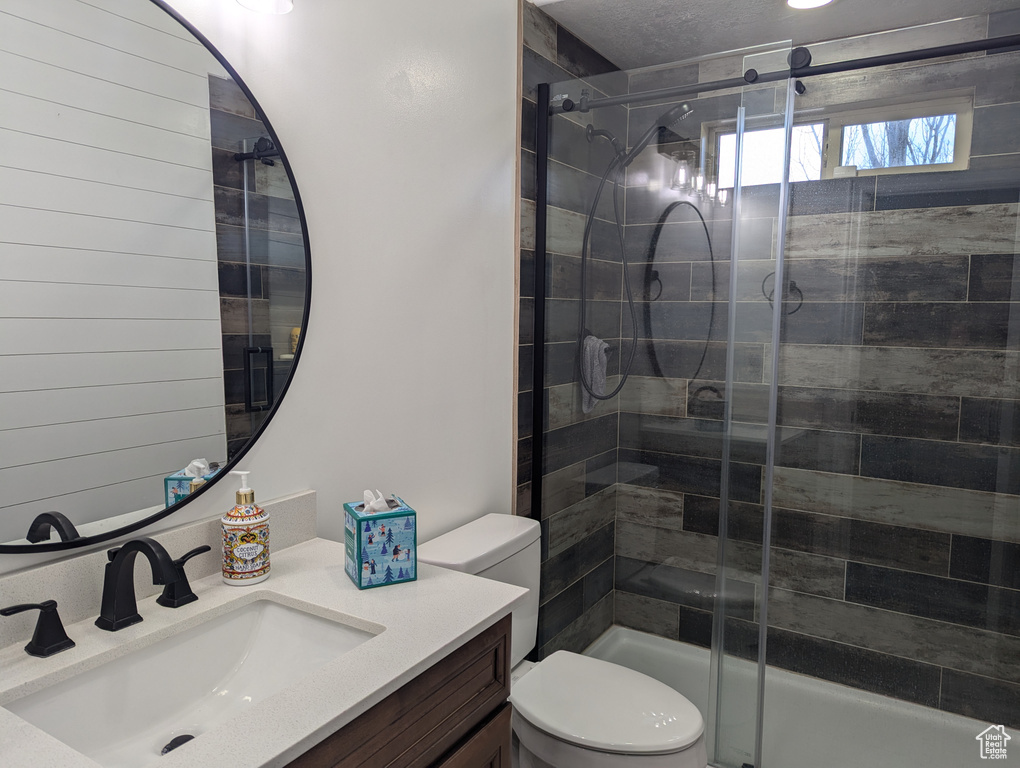 Full bath with toilet, a stall shower, and vanity