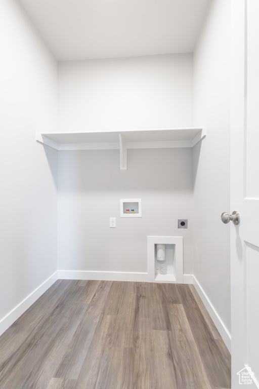 Clothes washing area featuring hookup for an electric dryer, wood finished floors, washer hookup, and baseboards