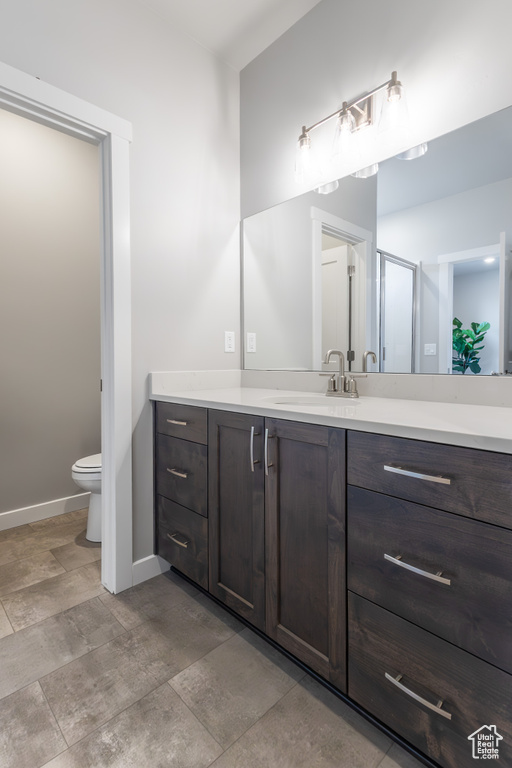 Full bath with vanity, baseboards, toilet, and a shower with shower door