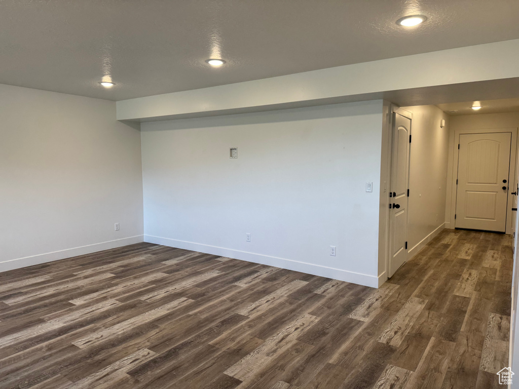 Empty room featuring dark wood-type flooring, baseboards, and recessed lighting