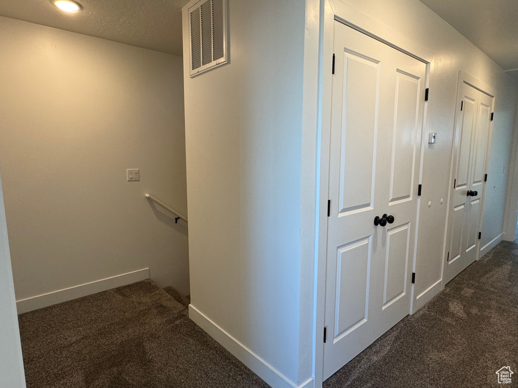 Hall with dark colored carpet, an upstairs landing, and baseboards