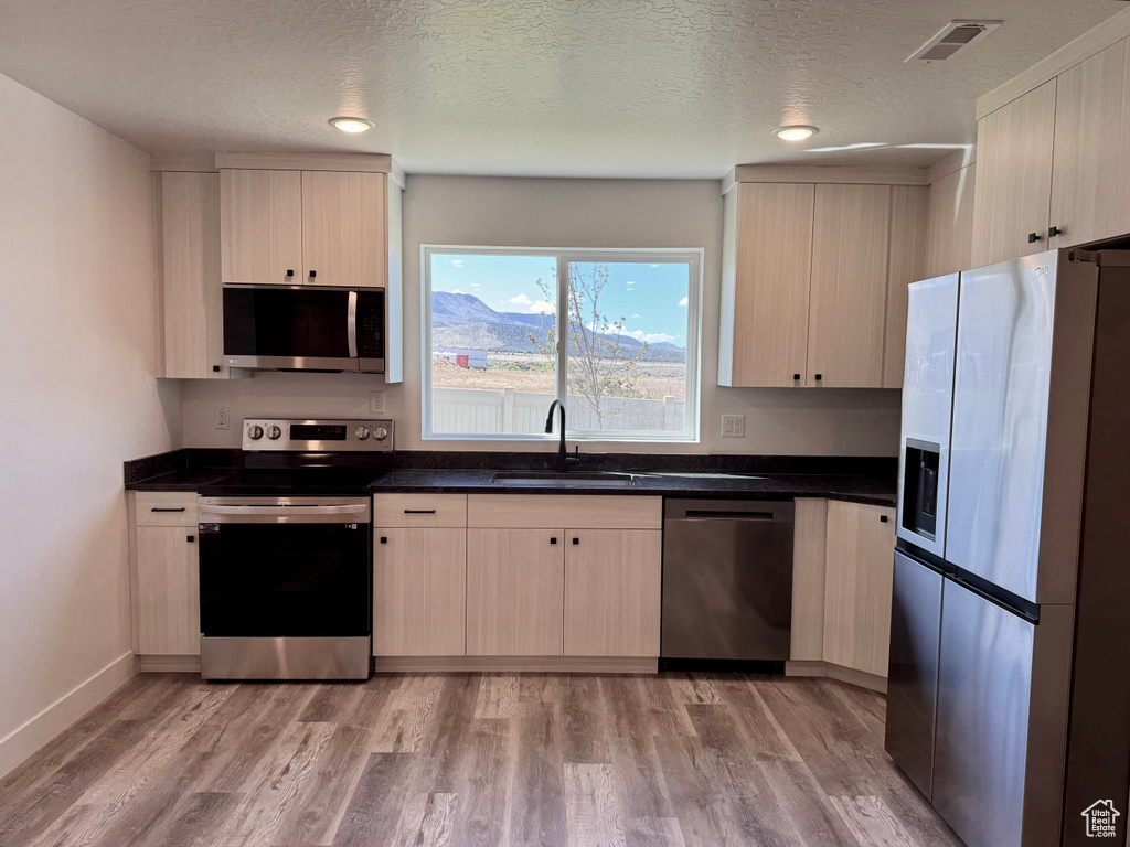 Kitchen featuring stainless steel appliances, a sink, dark countertops, a textured ceiling, and recessed lighting