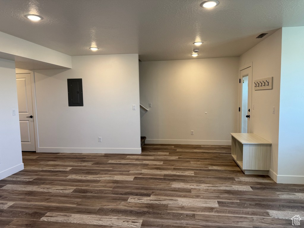 Finished below grade area with electric panel, dark wood-style flooring, baseboards, a textured ceiling, and recessed lighting