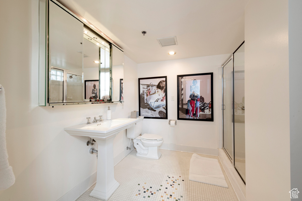 Full bathroom with toilet, baseboards, a shower with door, and tile patterned flooring