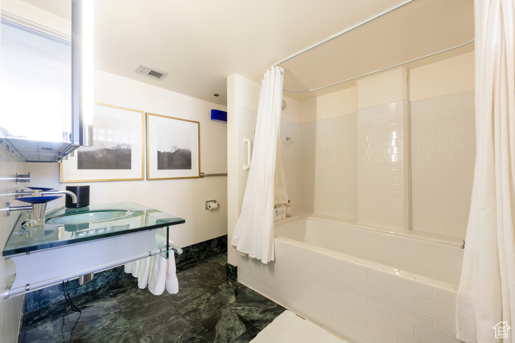 Bathroom with a sink and shower / bath combo with shower curtain