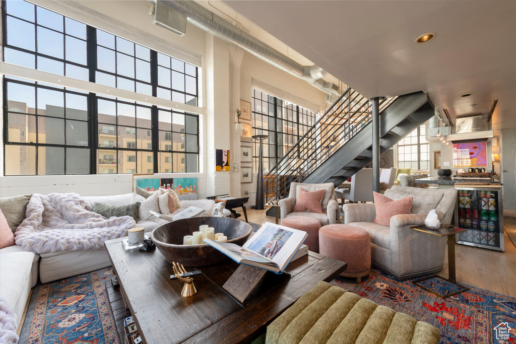 Living area with stairs, wood finished floors, a high ceiling, and recessed lighting