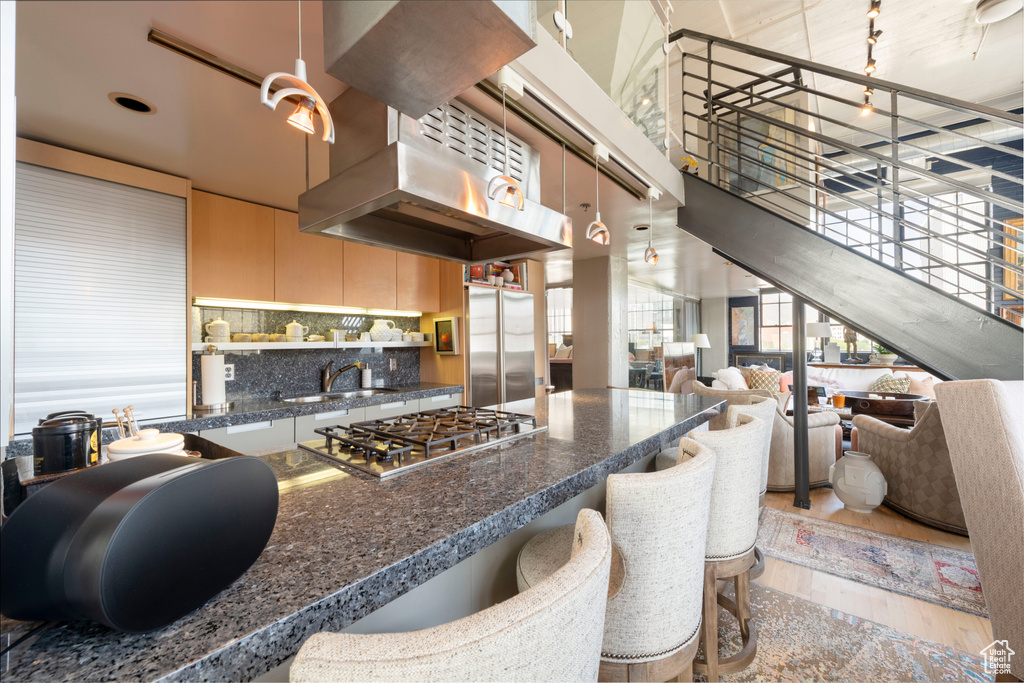 Kitchen featuring stainless steel appliances, dark countertops, light wood-style flooring, backsplash, and a high ceiling