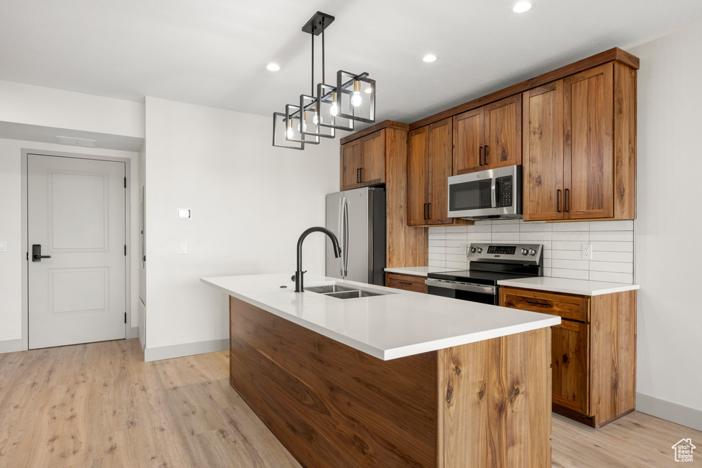 Kitchen with stainless steel appliances, brown cabinets, baseboards, a sink, and recessed lighting