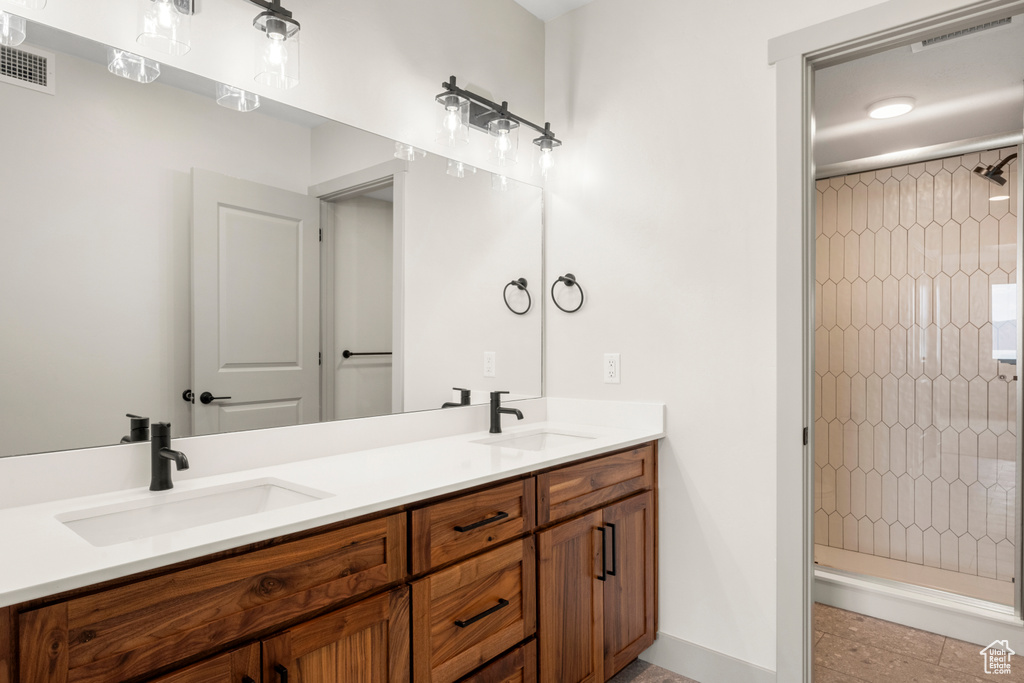 Bathroom featuring a stall shower, double vanity, and baseboards