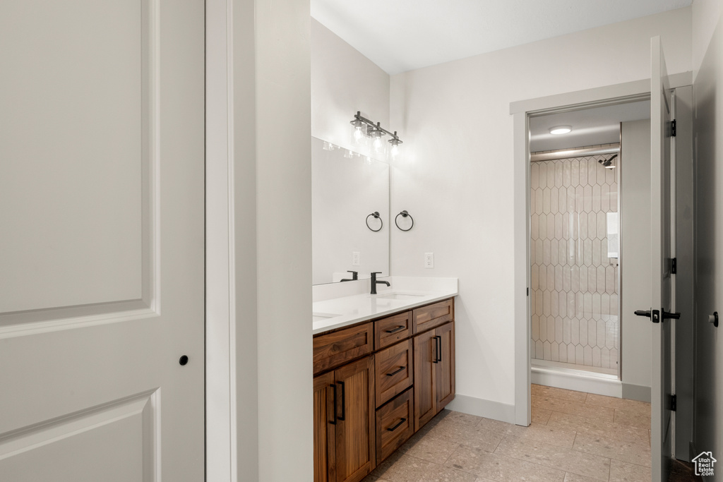 Full bath featuring a shower stall, double vanity, baseboards, and tile patterned flooring