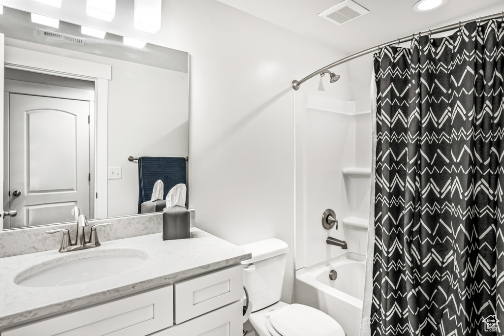 Bathroom featuring vanity, shower / bath combination with curtain, and toilet