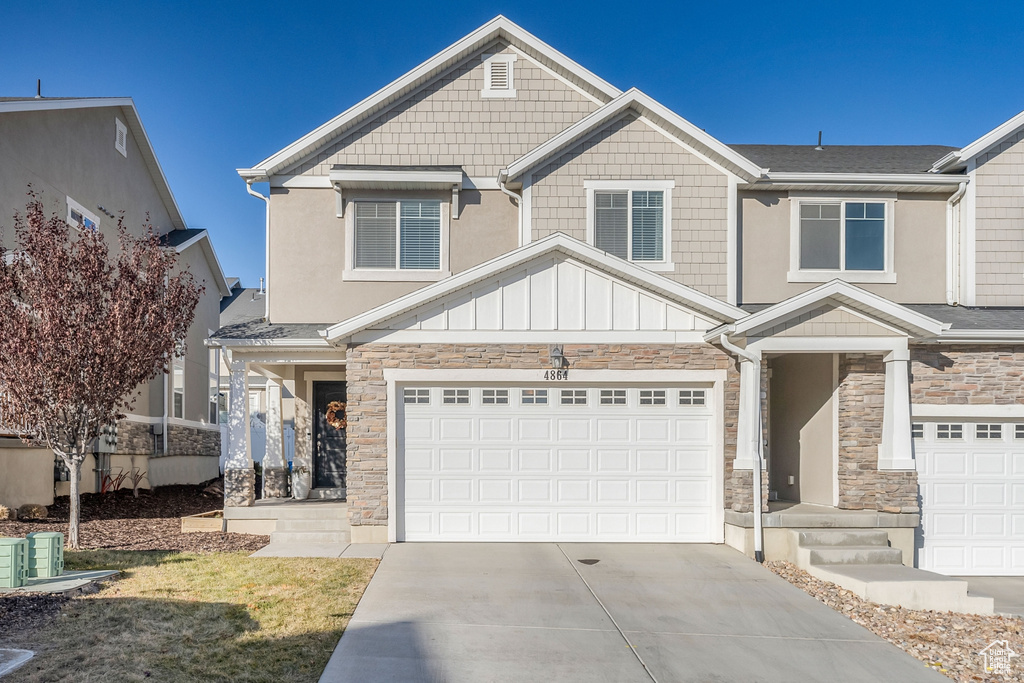 Craftsman house with stone siding, concrete driveway, a garage, and board and batten siding