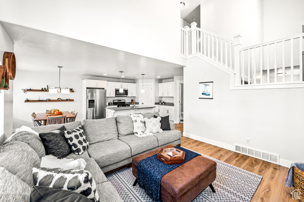 Living area with light wood-style flooring, baseboards, a high ceiling, stairway, and recessed lighting
