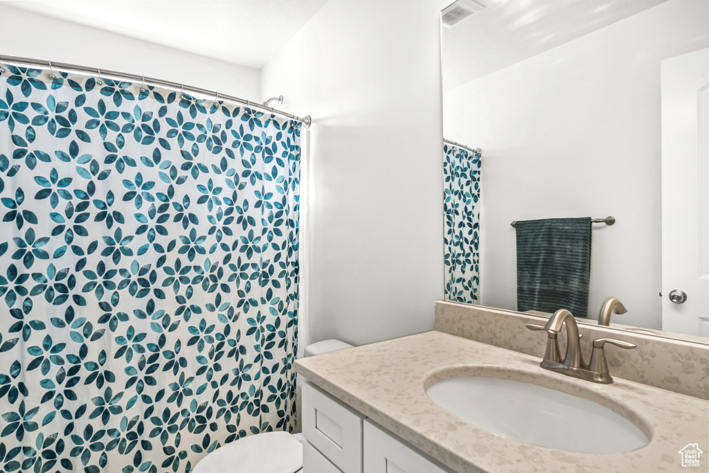Bathroom with toilet, vanity, and a shower with shower curtain