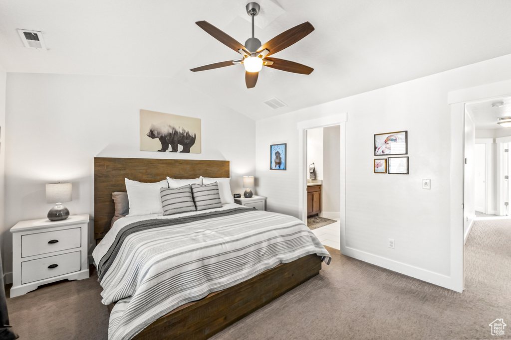 Carpeted bedroom with vaulted ceiling, baseboards, connected bathroom, and a ceiling fan