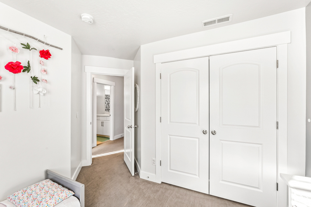 Bedroom featuring baseboards, light colored carpet, and a closet