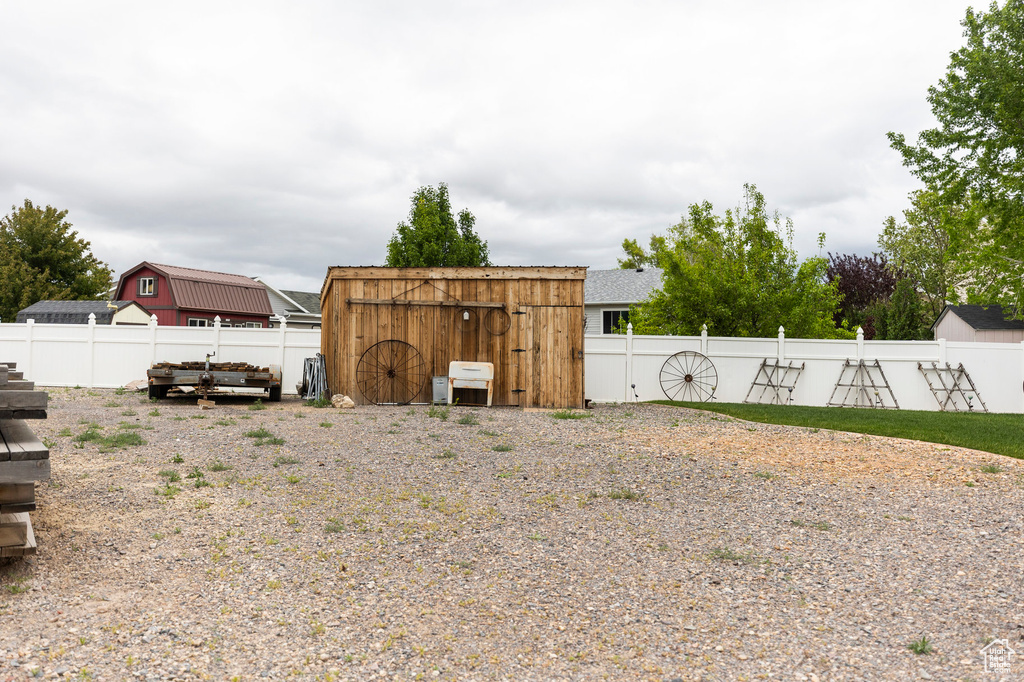 Fenced backyard featuring a storage unit and an outdoor structure