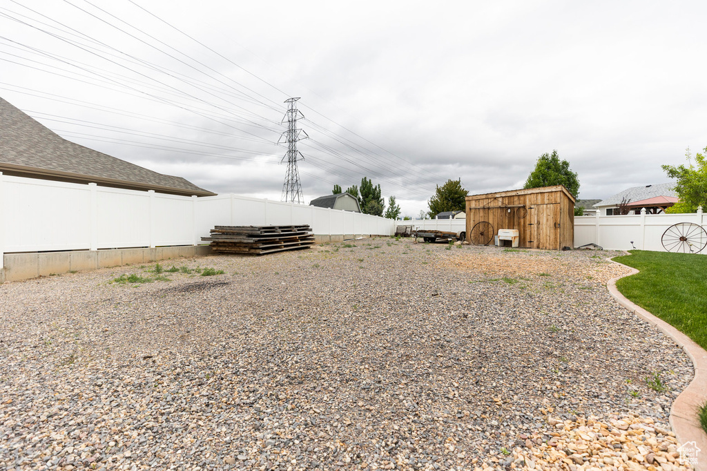 Fenced backyard featuring a storage shed and an outdoor structure