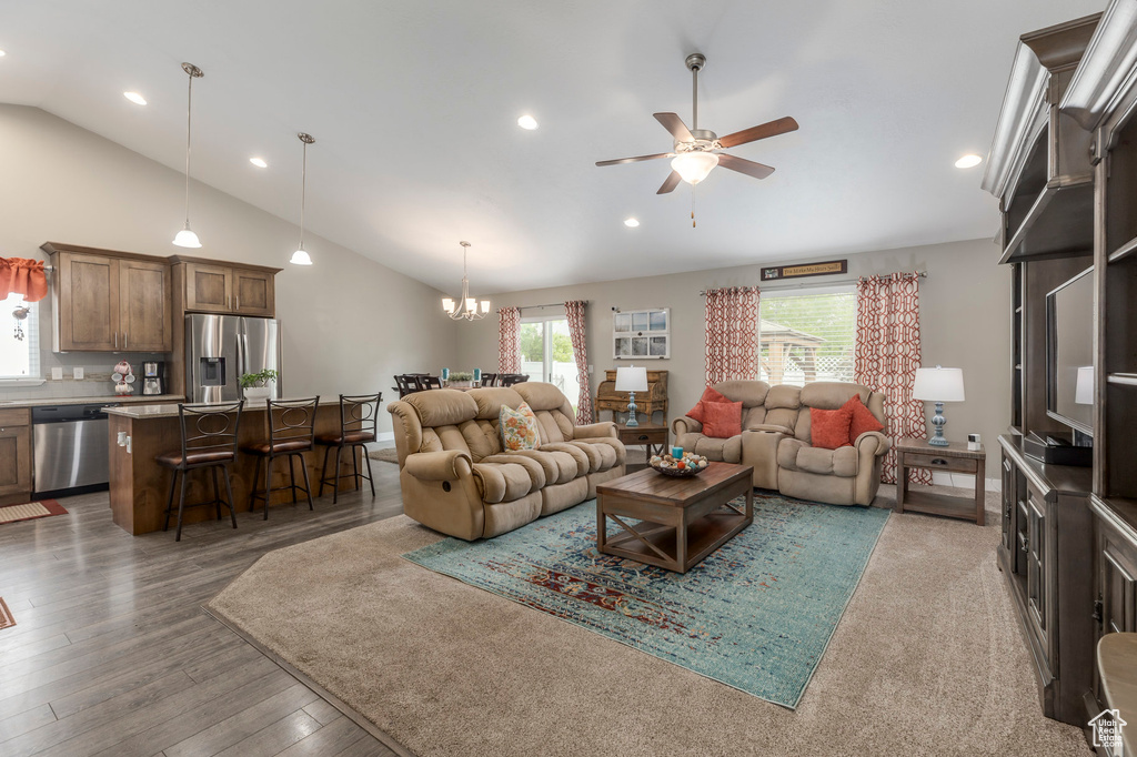Living room featuring lofted ceiling, a ceiling fan, a chandelier, recessed lighting, and wood finished floors