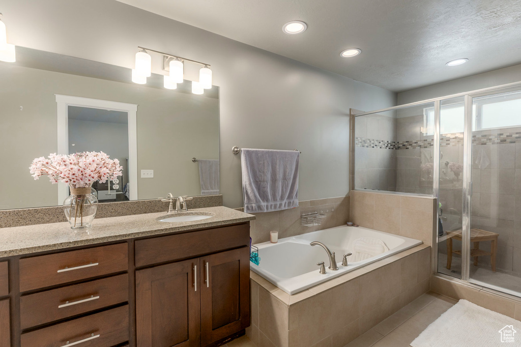 Bathroom featuring a shower stall, a garden tub, vanity, tile patterned flooring, and recessed lighting