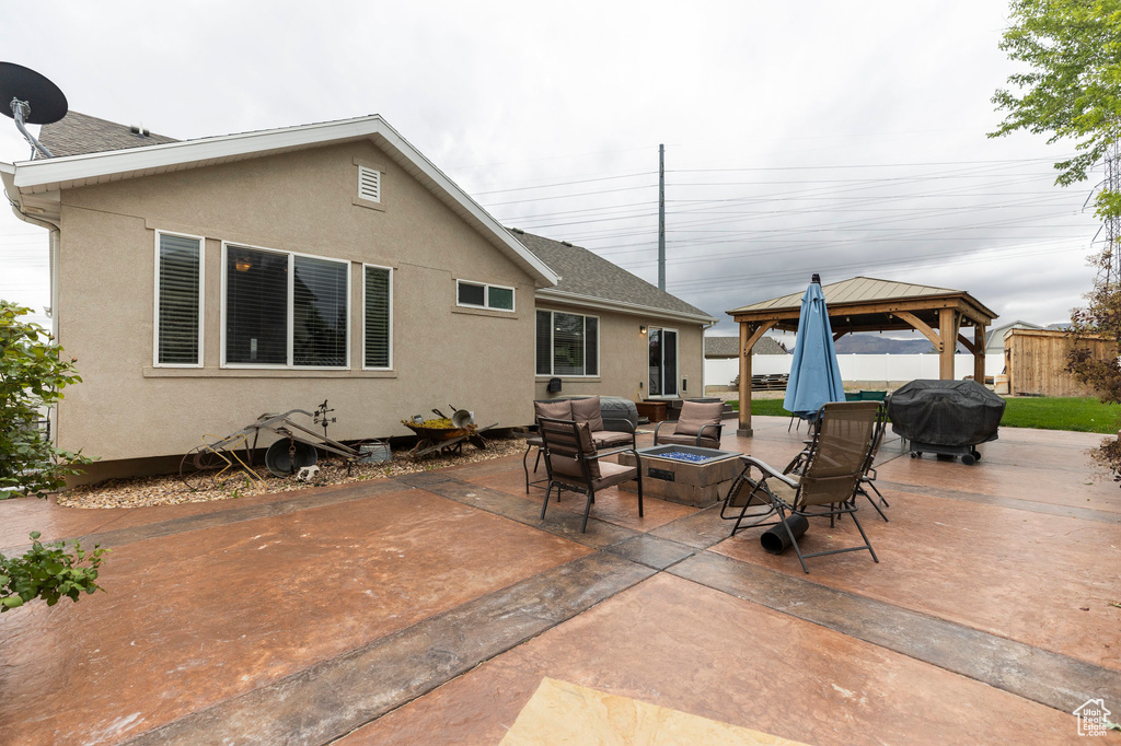 Rear view of house featuring a gazebo, a patio area, stucco siding, and a shingled roof