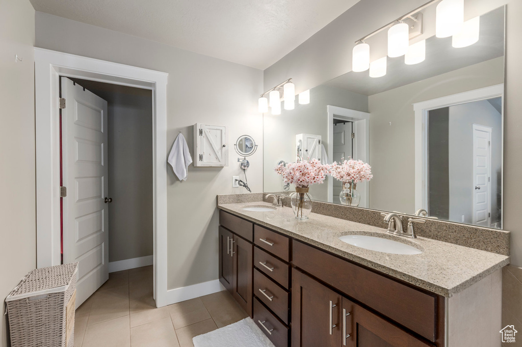 Bathroom with tile patterned floors, double vanity, and baseboards