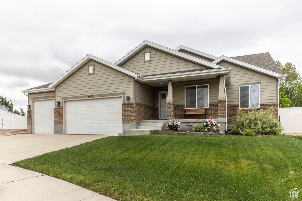 View of front of home featuring brick siding, an attached garage, a porch, a front yard, and concrete driveway