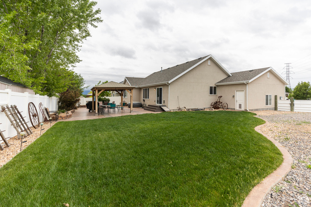 Rear view of property featuring a gazebo, stucco siding, and a patio area