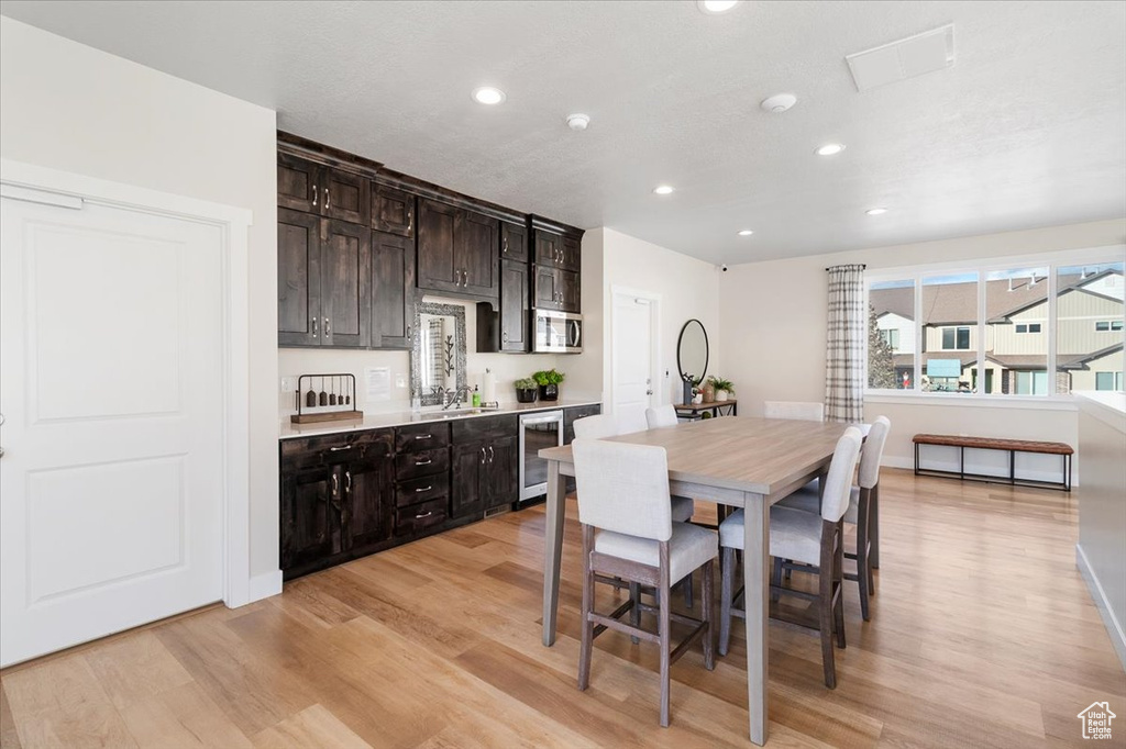 Dining room featuring wine cooler, light wood-style flooring, and recessed lighting