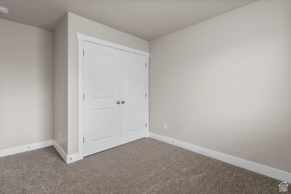 Unfurnished bedroom with carpet flooring, baseboards, and a closet