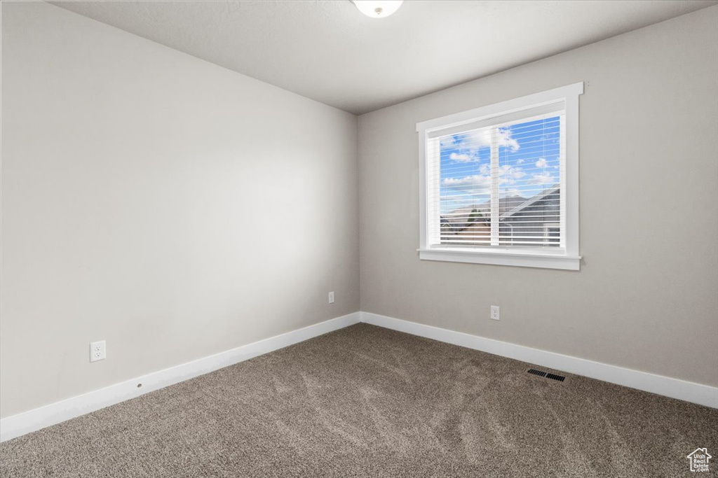 Unfurnished room with dark carpet and baseboards