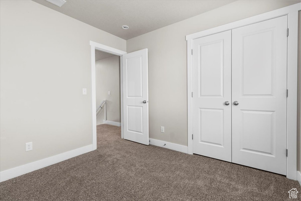 Unfurnished bedroom featuring carpet flooring, a closet, and baseboards