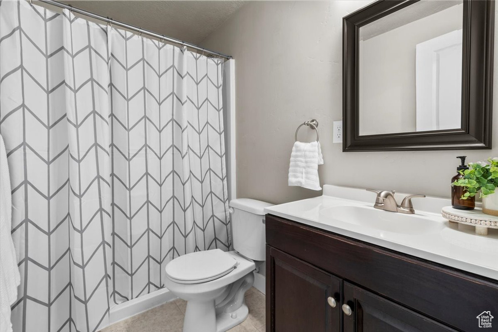 Full bath featuring vanity, toilet, curtained shower, and tile patterned flooring