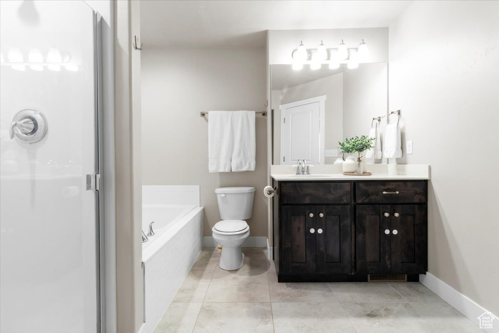 Bathroom featuring a garden tub, a stall shower, toilet, and baseboards