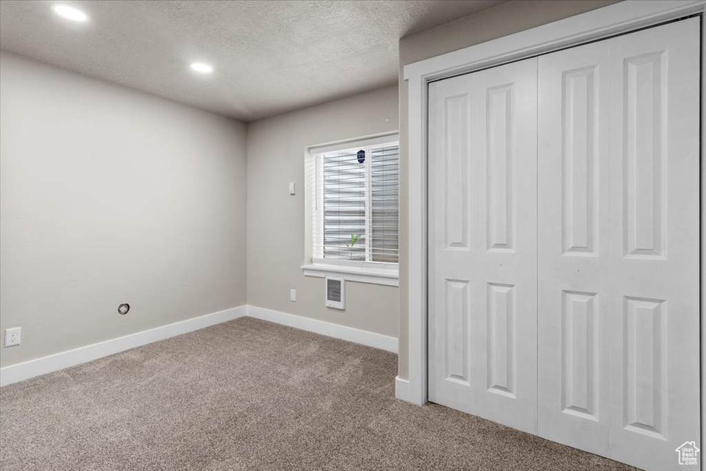 Unfurnished bedroom with carpet, baseboards, recessed lighting, a textured ceiling, and a closet