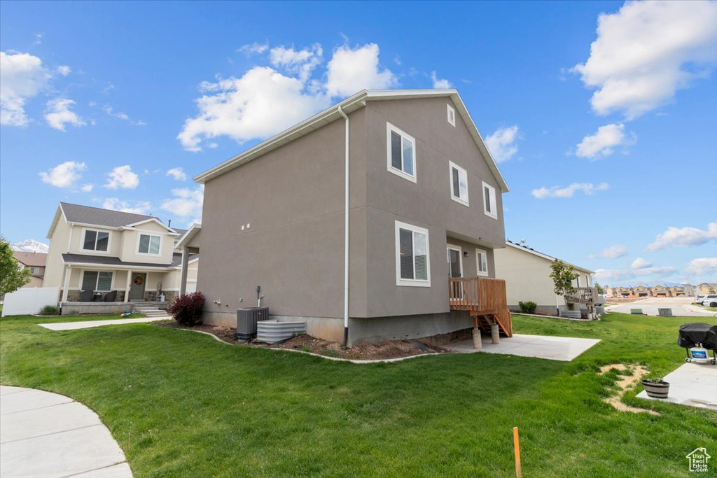 Rear view of property with stucco siding, cooling unit, a yard, a residential view, and a patio