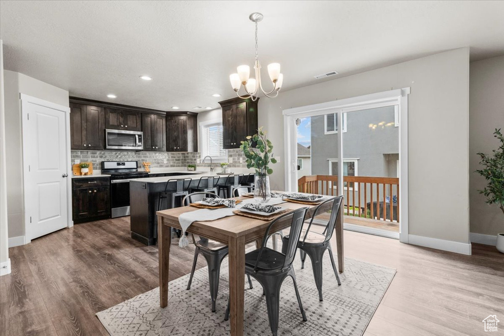 Dining space with a chandelier, light wood-style flooring, baseboards, and recessed lighting