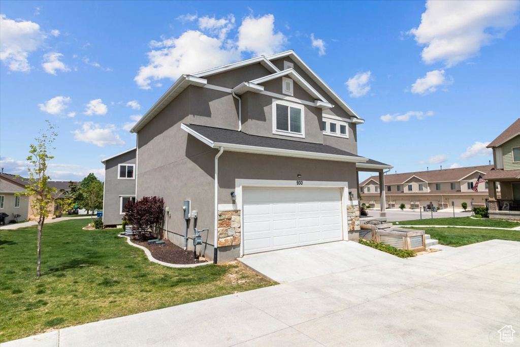 View of front of home with stucco siding, an attached garage, a front lawn, driveway, and stone siding