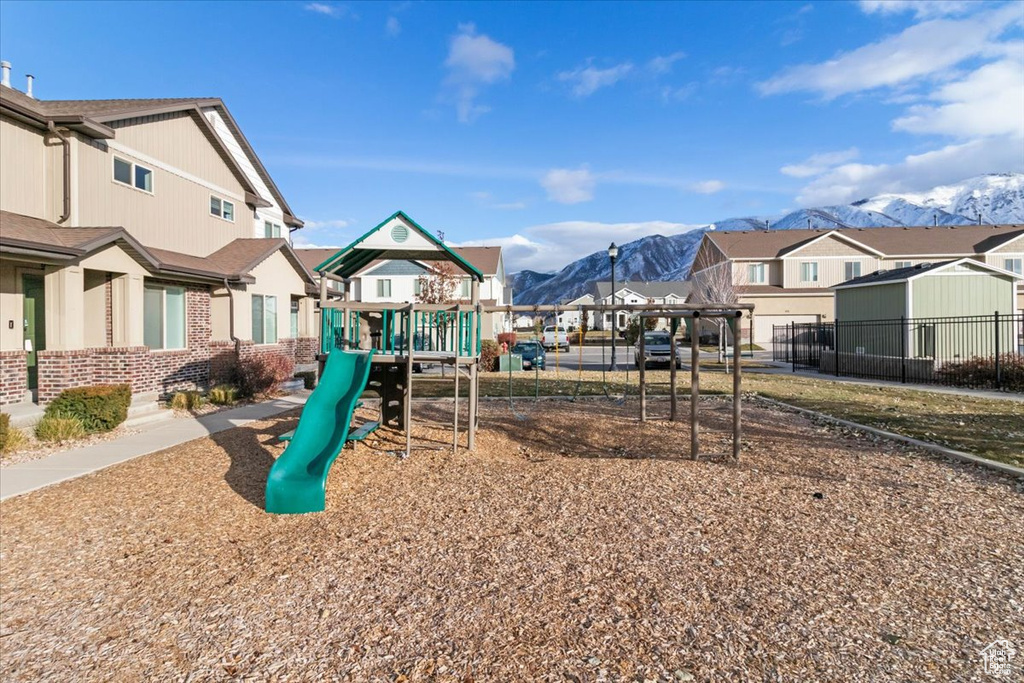 View of jungle gym with a mountain view, a residential view, and fence