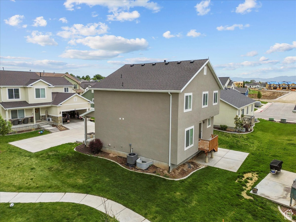 Back of property featuring stucco siding, a residential view, a lawn, a shingled roof, and a patio