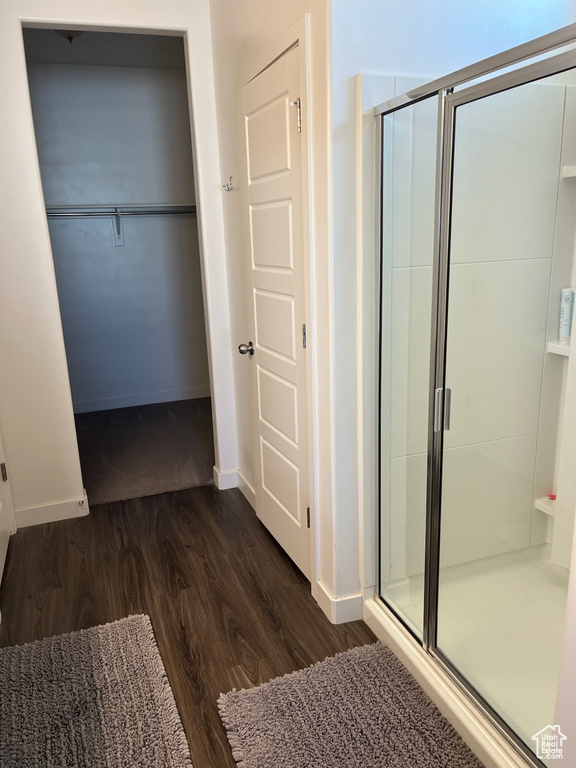 Bathroom with wood finished floors, a stall shower, baseboards, and a spacious closet