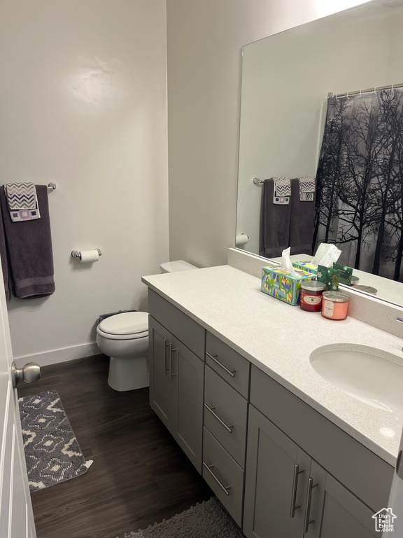 Full bath featuring baseboards, wood finished floors, toilet, and vanity