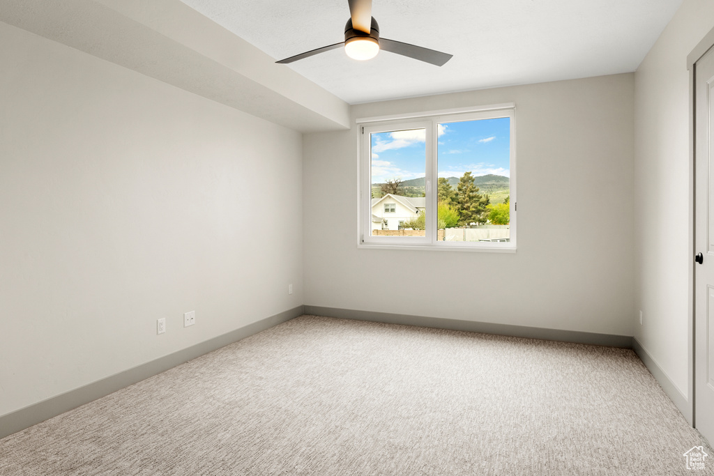 Empty room with a ceiling fan, carpet, and baseboards