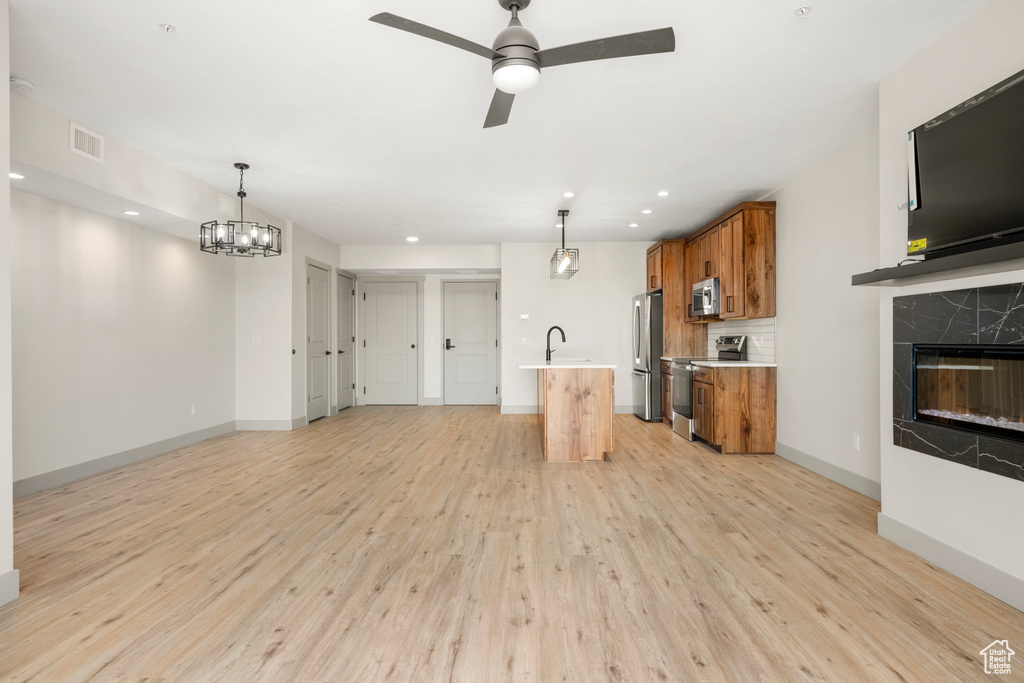 Kitchen with stainless steel appliances, brown cabinets, light wood-style flooring, light countertops, and recessed lighting