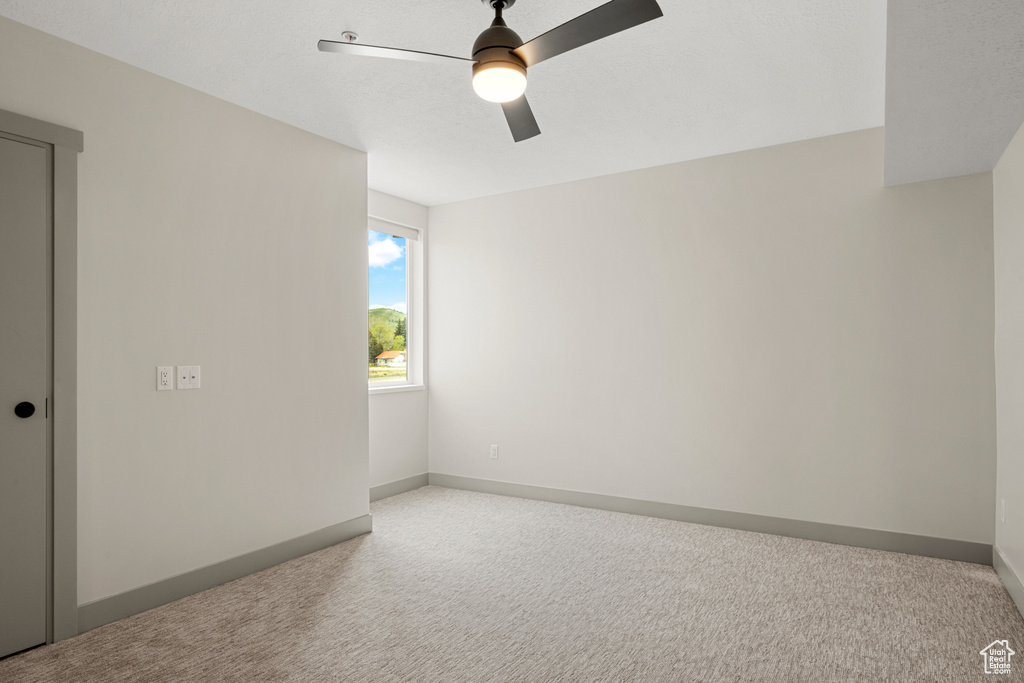 Carpeted empty room with ceiling fan and baseboards