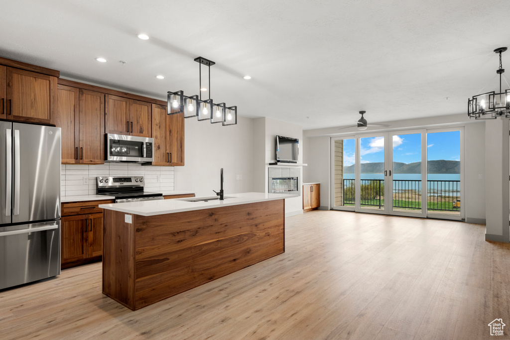 Kitchen featuring stainless steel appliances, a sink, open floor plan, decorative backsplash, and recessed lighting