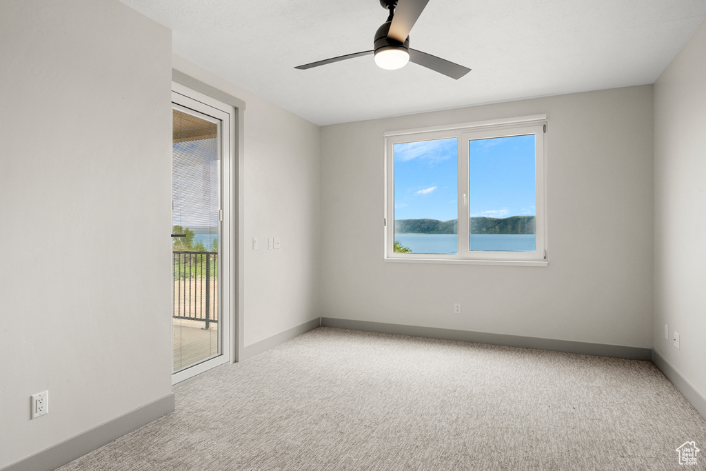 Carpeted empty room featuring baseboards and ceiling fan