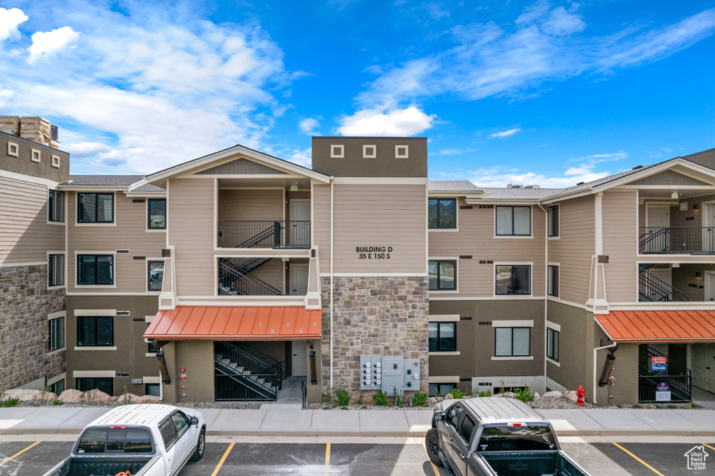 View of apartment building / complex featuring uncovered parking and stairway