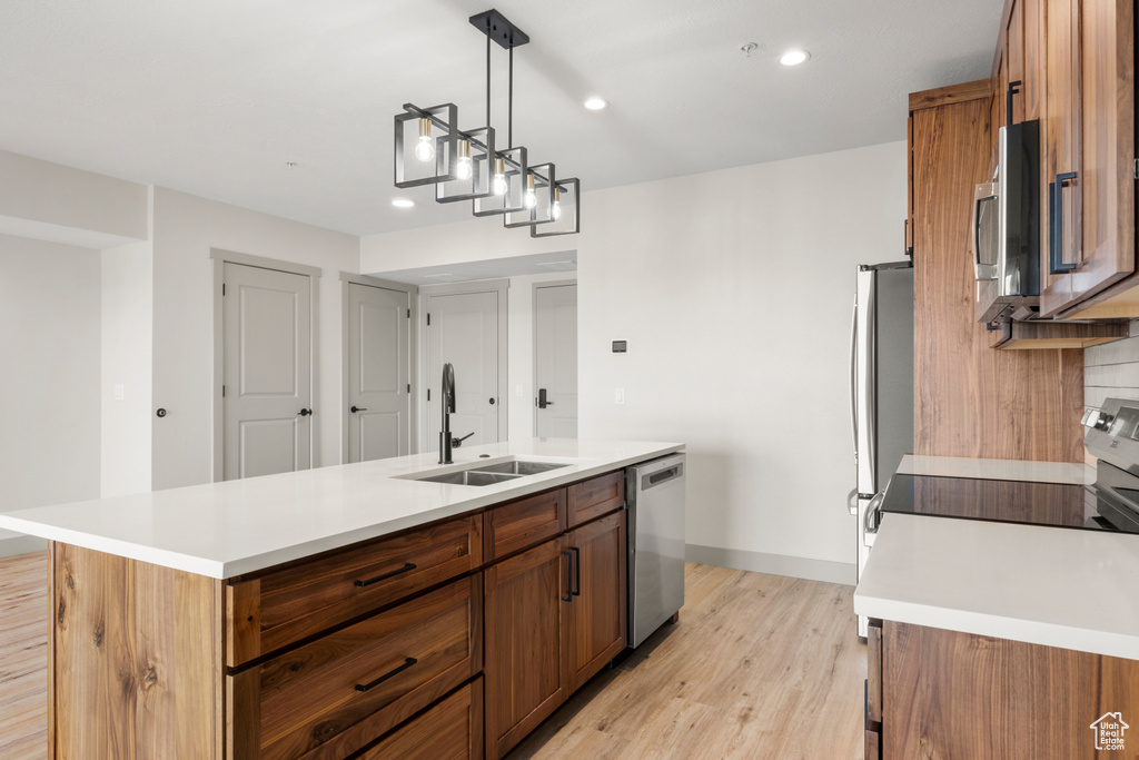 Kitchen featuring a sink, appliances with stainless steel finishes, brown cabinets, light wood finished floors, and recessed lighting